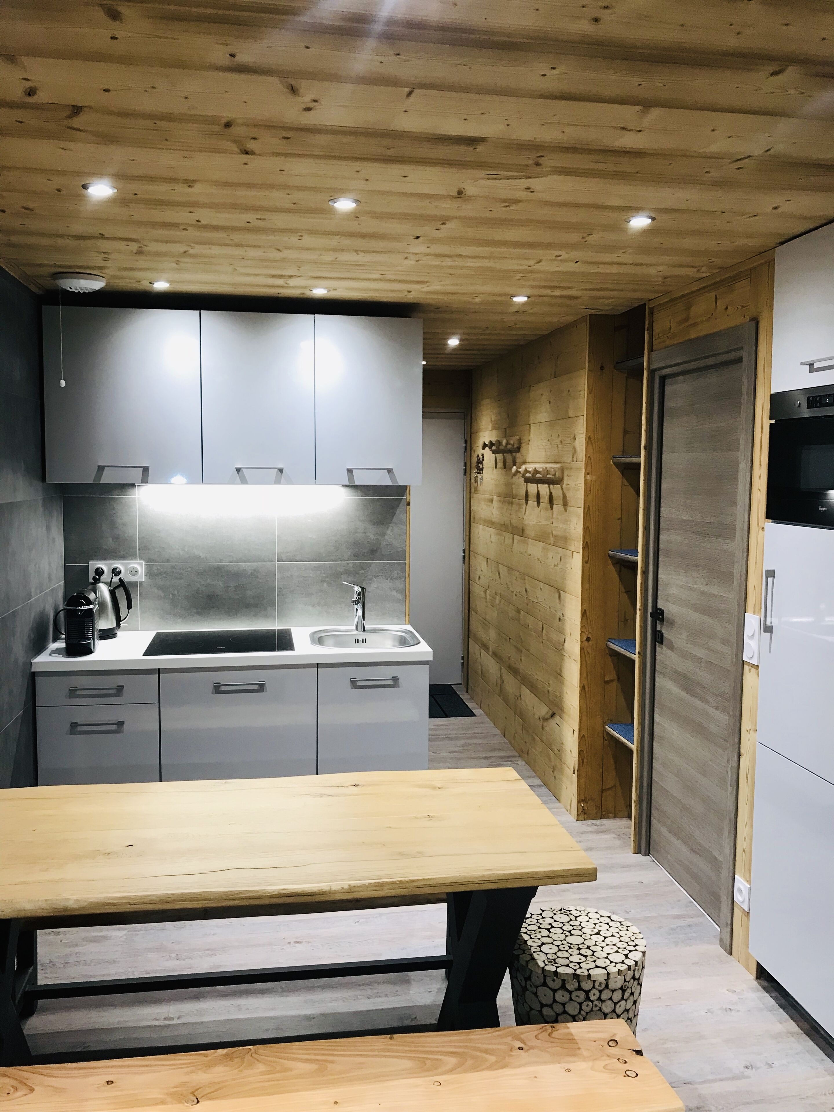 Une cuisine moderne avec des armoires grises, un plafond en bois et un four encastré.