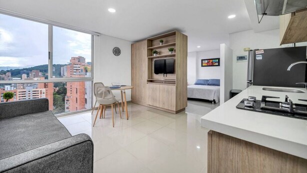 Un appartamento moderno con balcone, angolo ristoro, angolo cottura e un letto.