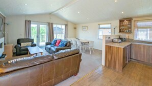 A spacious living area with a leather sofa, a dining table, and a kitchen area with a toaster.