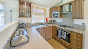A modern kitchen with wooden cabinets, a gas stove, a built-in oven, and a window with blinds.