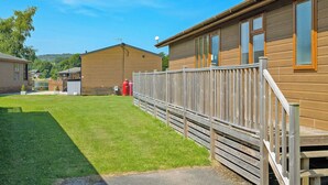 A row of wooden cabins with a fenced yard and a clear sky.