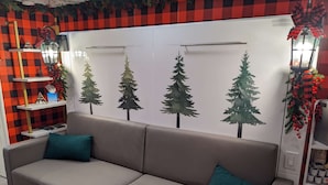 Un canapé beige avec des coussins turquoise, dans une pièce dont le mur est à carreaux et qui est décorée pour Noël.