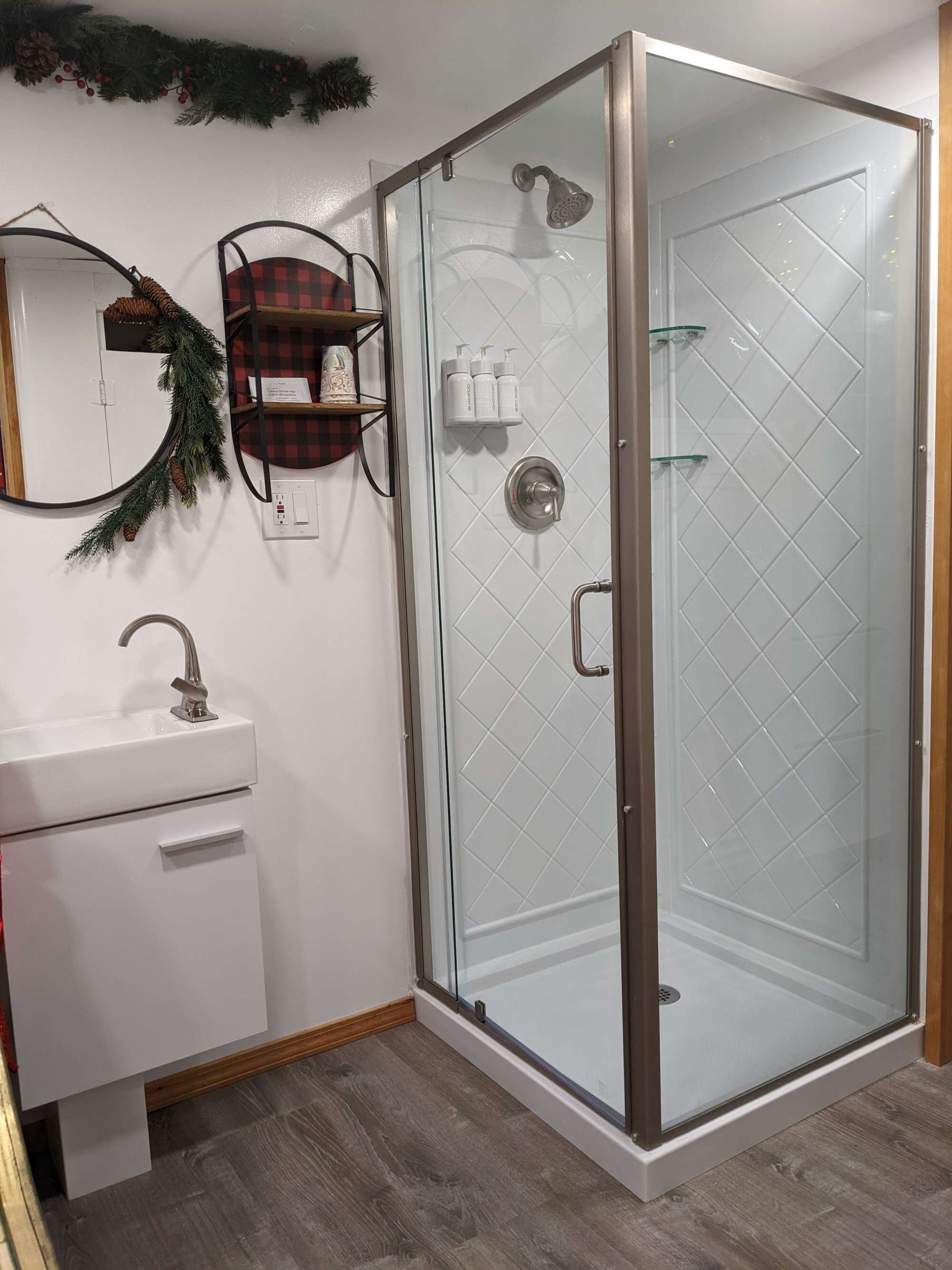Un baño moderno con ducha envuelta en vidrio, un lavamanos blanco y un espejo.