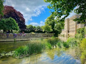 A serene riverside scene with a historic building, lush greenery, and a clear sky. - Cosy 3-bedroom home with garden and log burner, close to the City of Bath. (Bradford On Avon)