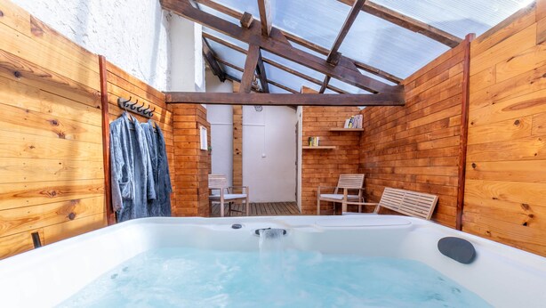 Eine Holzblockhütte mit Whirlpool, Holzwänden und einer kleinen Sitzecke.