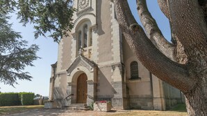 Eine historische Kirche mit einem markanten Glockenturm, Rundbogenfenstern und einer großen Holztür.