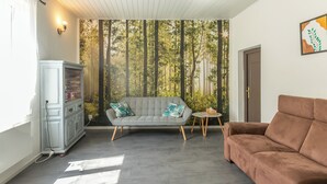 Ein Wohnzimmer mit grauem Sofa, braunem Sofa, weißem Schrank und einem kleinen runden Tisch.