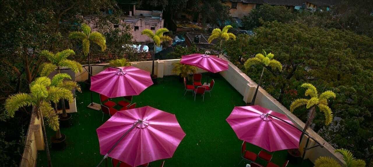 An outdoor patio with green artificial turf, red chairs, and pink umbrellas.