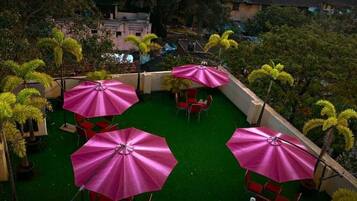 An outdoor patio with green artificial turf, red chairs, and pink umbrellas.