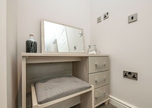 Une chambre à coucher avec un lit en bois, une table de chevet avec une lampe, un miroir et une petite commode avec des tiroirs.