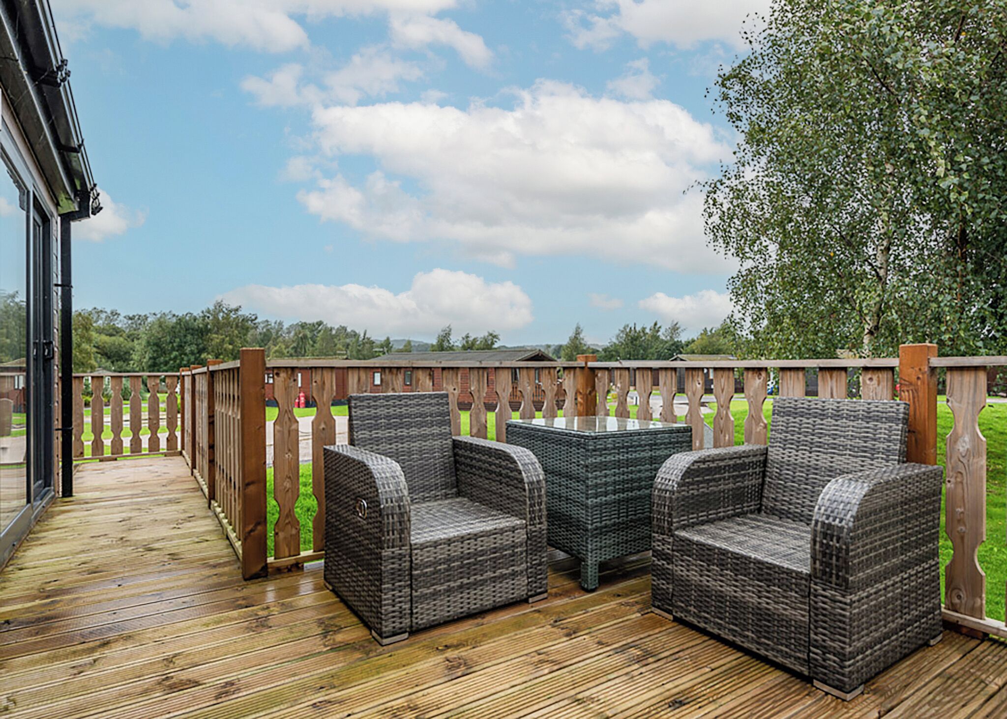 A deck with wicker furniture and a wooden railing.