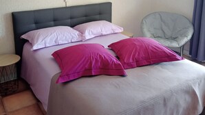 A bedroom with a bed, pillows, a chair, and wall art.