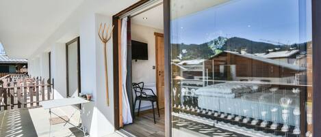 Une chambre d’hôtel moderne dotée d’une grande porte-fenêtre coulissante donnant sur un balcon avec vue sur les montagnes.