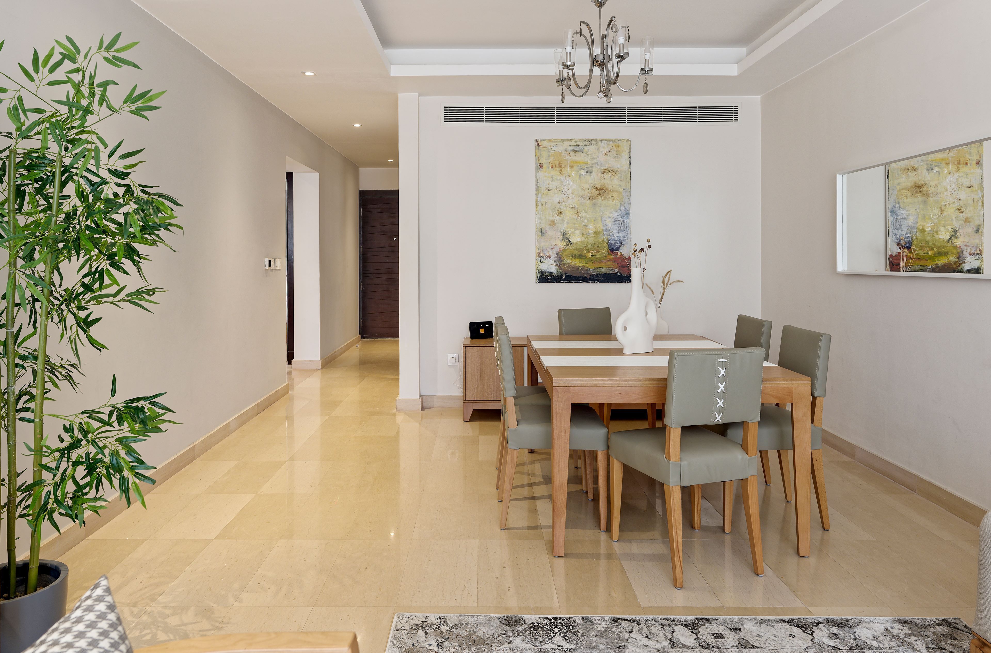 A modern dining area with a wooden table and chairs, a potted plant, and abstract paintings on the walls.