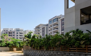 A modern residential building with multiple balconies, a paved driveway, and lush greenery. - VESTA - Cairo Festival City Residence (New Cairo)