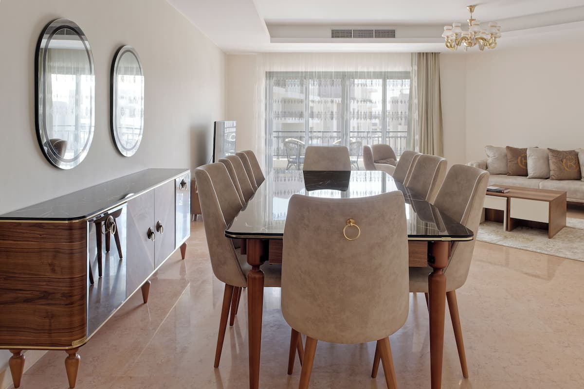 A modern dining area with a glass-top table, six chairs, and a wooden cabinet.