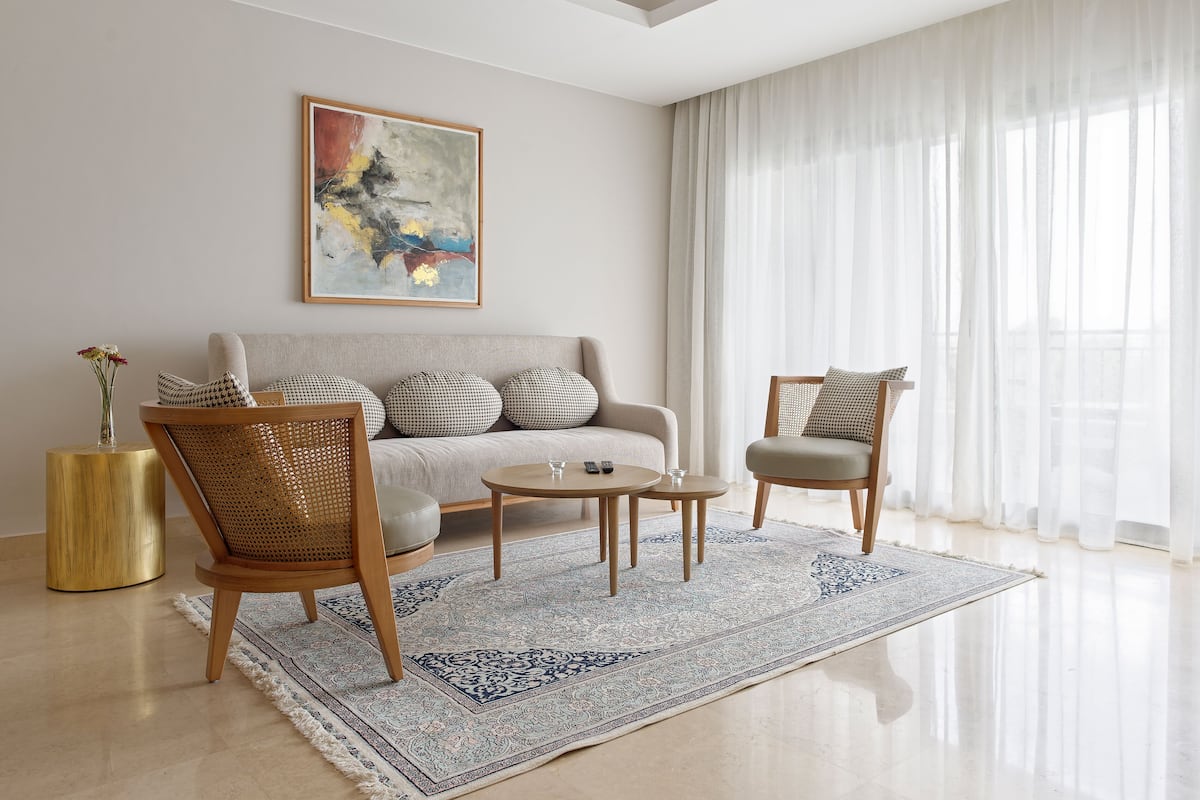 A modern living room with a sofa, two armchairs, a coffee table, and a rug.