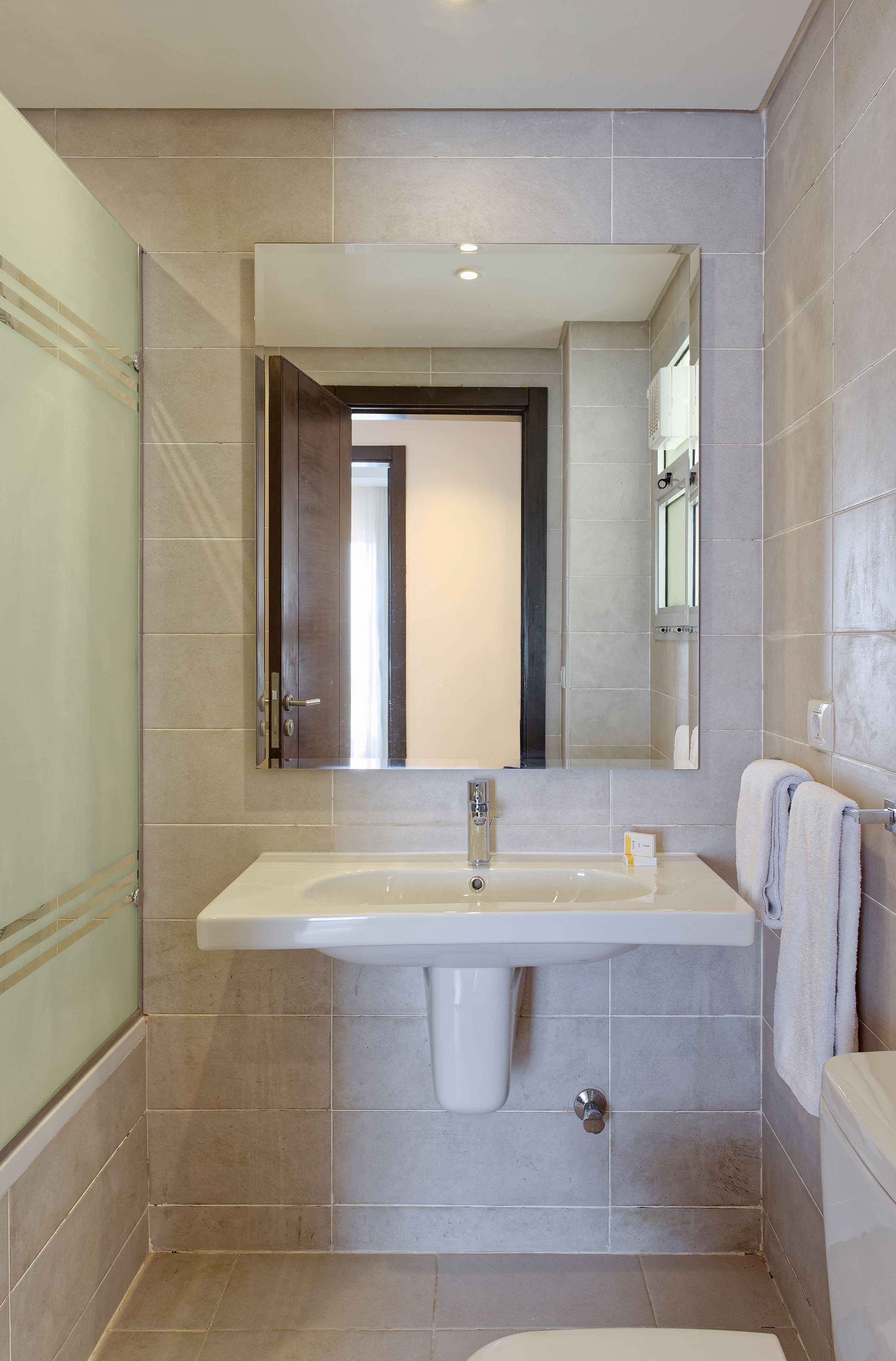 Un bany amb un mirall gran, un lavabo i un vàter.