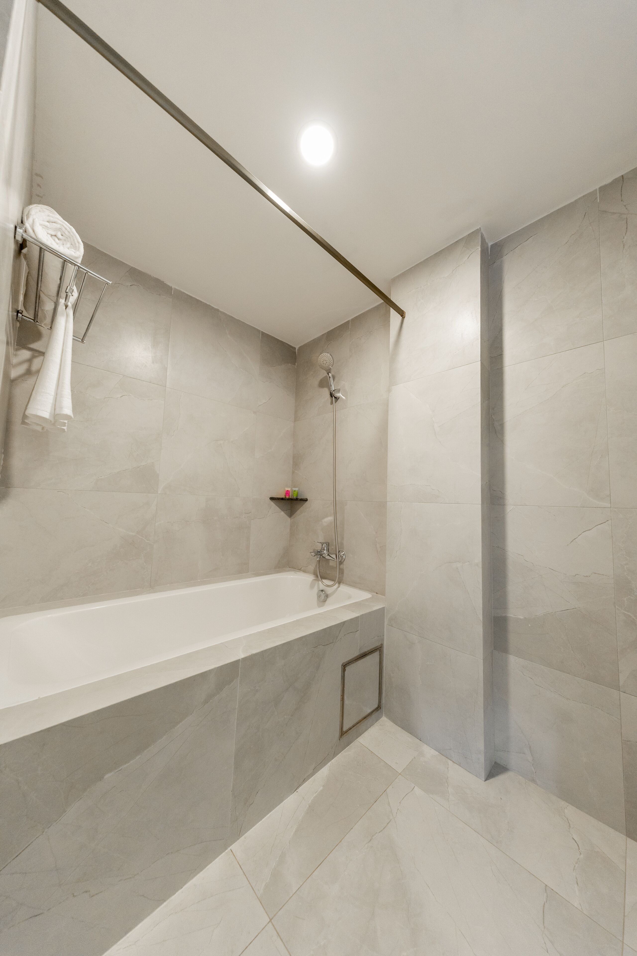A modern bathroom with a bathtub, shower, and a towel rack.