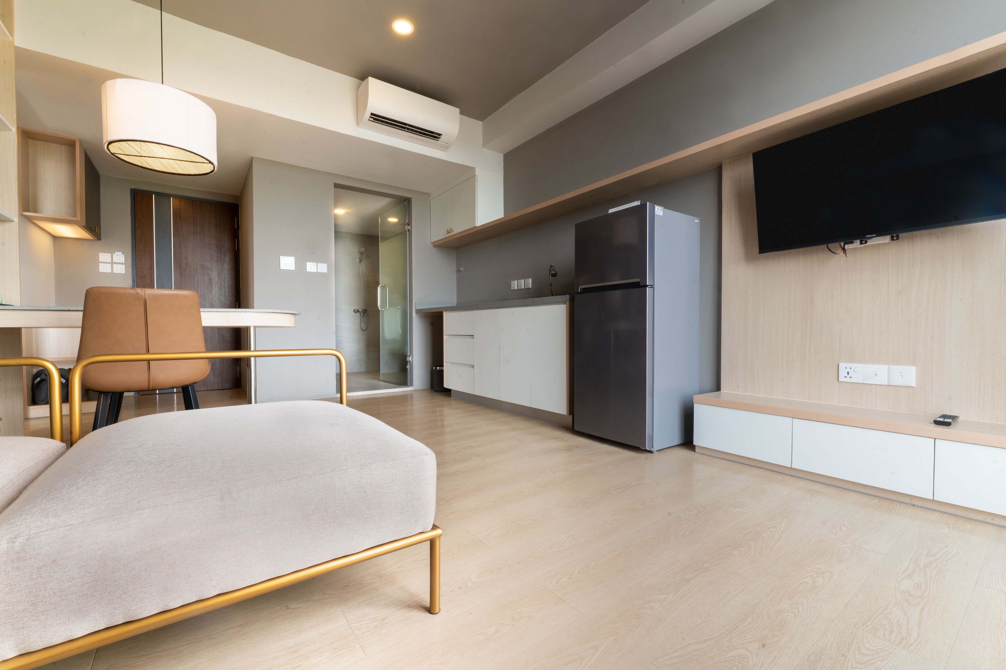 A modern kitchen with a built-in refrigerator, a flat-screen TV mounted on the wall, and a dining area with a table and chairs.