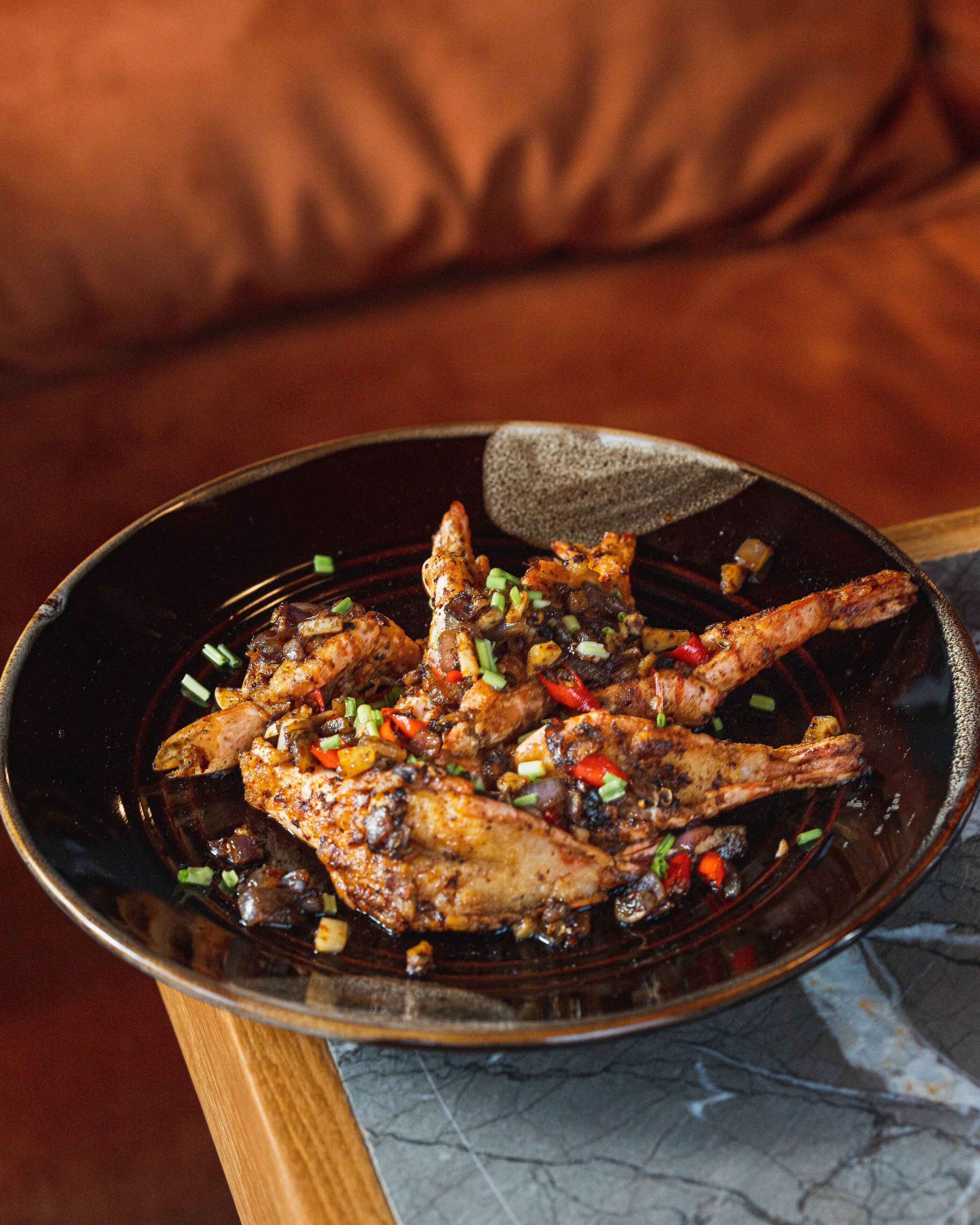 A dish of grilled chicken with vegetables on a dark plate.