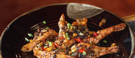 A dish of grilled chicken with vegetables on a dark plate.