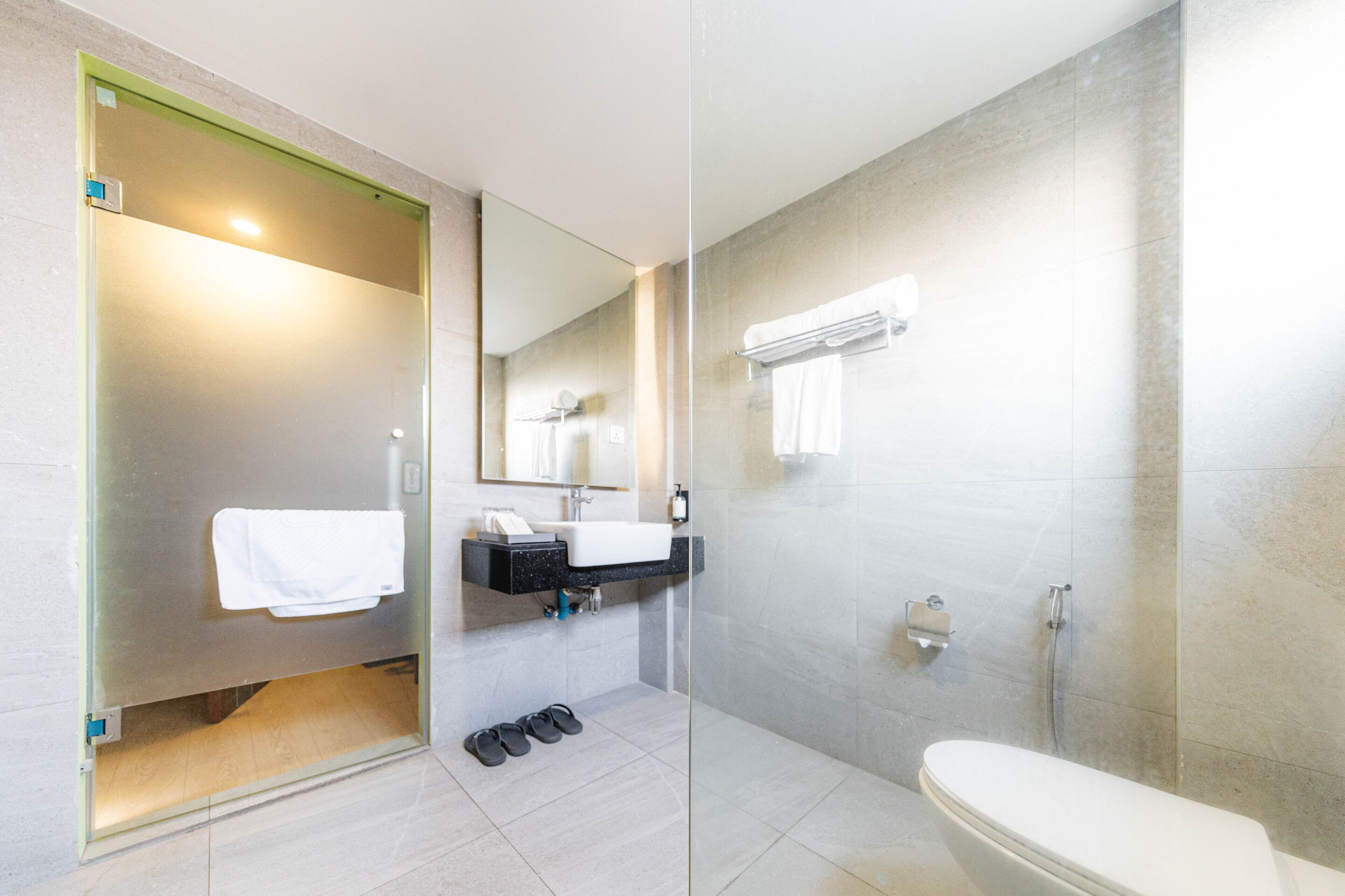 A modern bathroom with a glass-enclosed shower, a white toilet, and a sink with a mirror above it.