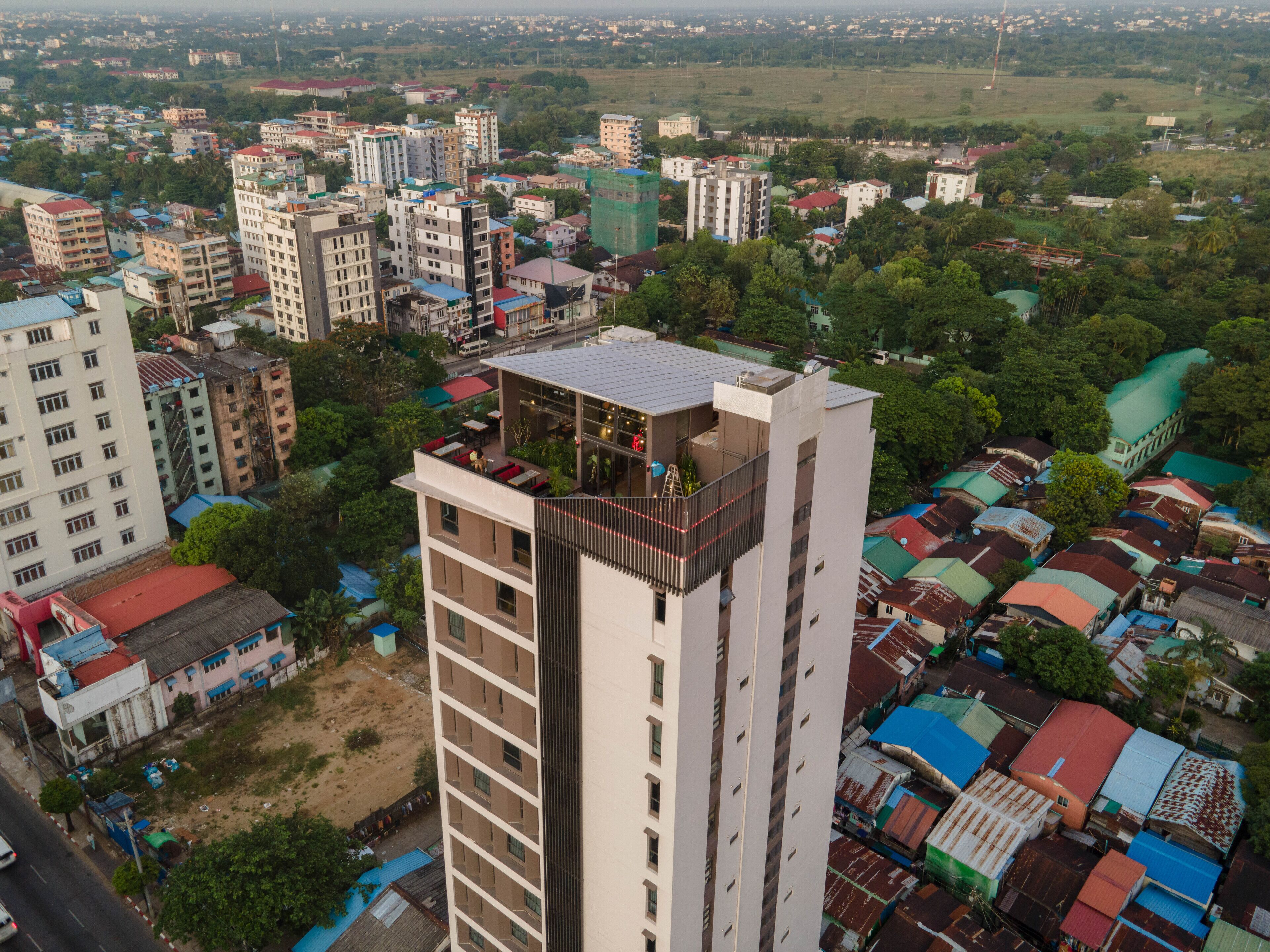 A high-rise building with multiple floors, balconies, and a rooftop terrace.