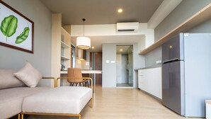 A modern living room with a sofa, a dining area with a table and chairs, and a kitchen with a refrigerator. - Areca Hotel (Yangon)