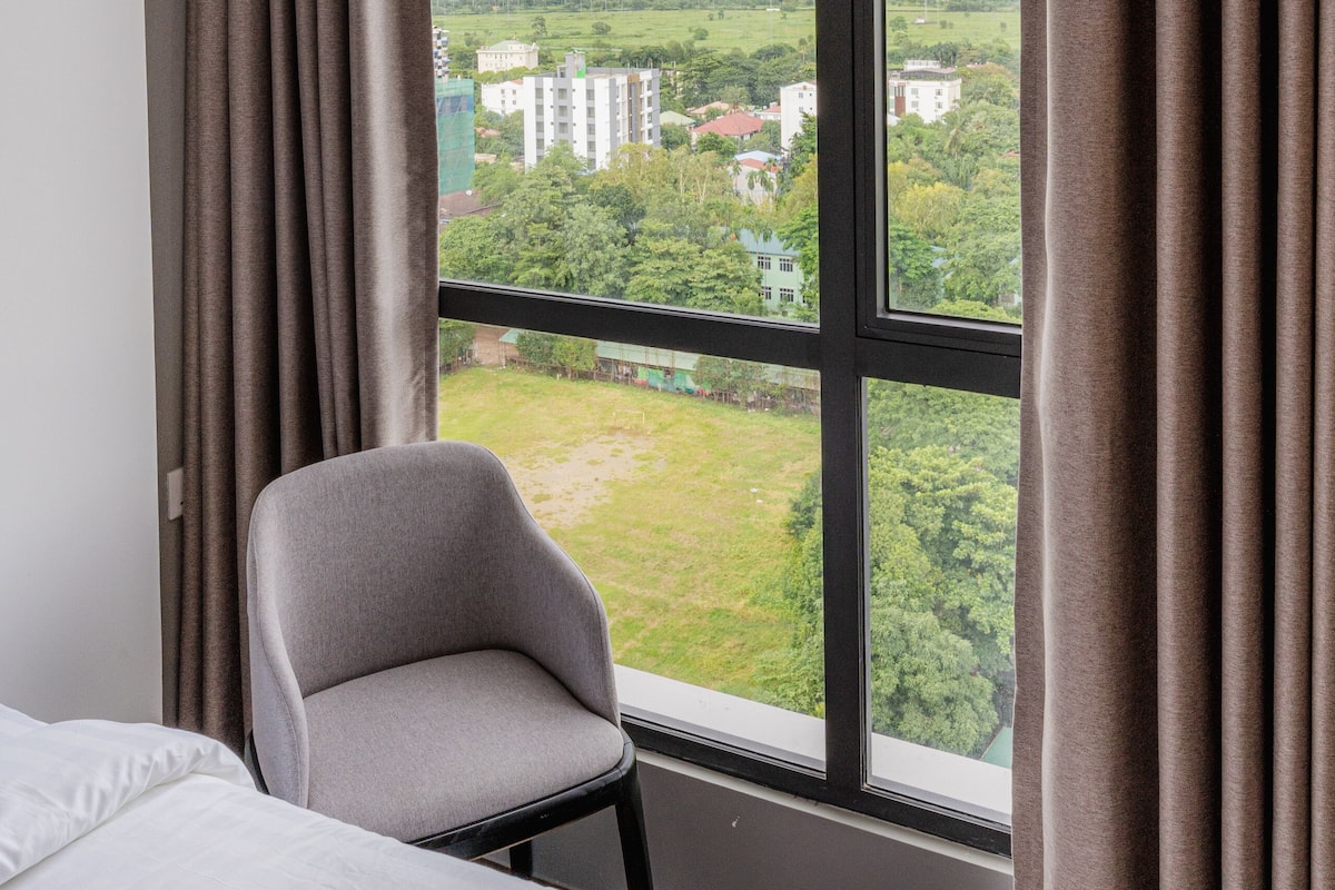Una habitación de hotel con un ventanal grande, una silla y una cama.