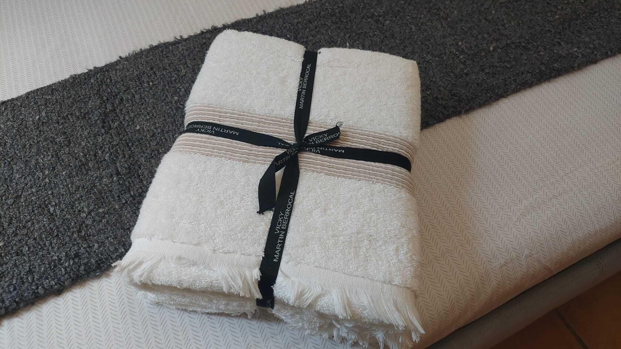 A neatly folded towel with a black ribbon tied around it, placed on a textured surface.