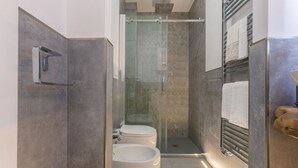 Et moderne badeværelse med en glasafskærmet brusekabine, toilet og bidet.