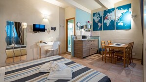 Ein Hotelzimmer mit Bett, Schreibtisch, Esstisch, Fernseher, Mikrowelle und einer Weltkarte an der Wand.