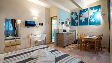 Ein Hotelzimmer mit Bett, Schreibtisch, Esstisch, Fernseher, Mikrowelle und einer Weltkarte an der Wand.