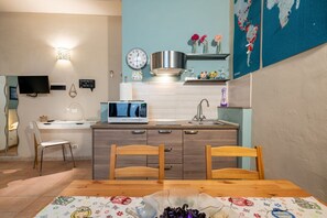 A modern kitchen with a microwave, sink, and wooden chairs at a dining table.