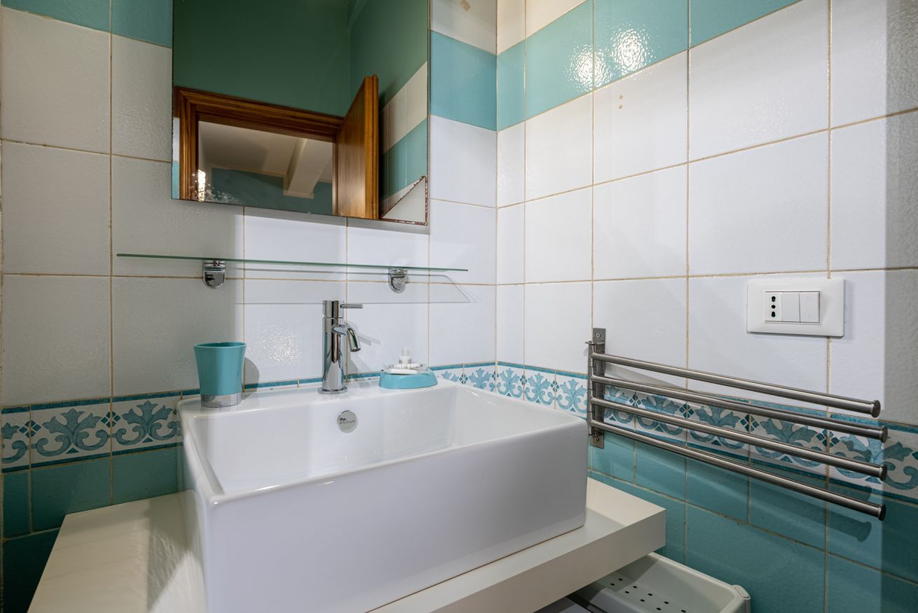 Ein Badezimmer mit einer weißen Badewanne, einer Glasablage, einer blauen Tasse und einem Handtuchhalter.