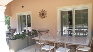 Un patio al aire libre con una mesa y sillas, un adorno en la pared y macetas con plantas.
