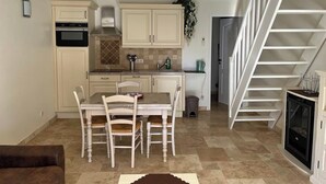 Una cocina compacta con una mesa y sillas, horno empotrado y una escalera que sube a un nivel superior.