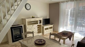 Una sala de estar con mesa de comedor, sillas, televisor y chimenea.