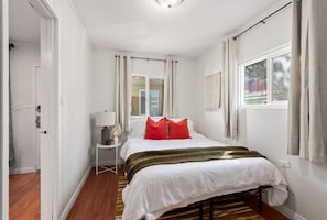 A bedroom with a bed, a nightstand, a lamp, and a window with curtains.