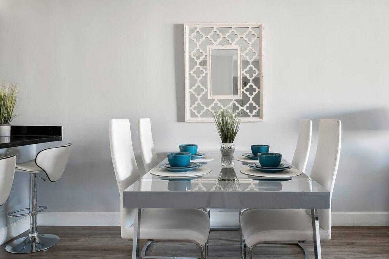 A modern dining area with a rectangular table, white chairs, and blue bowls.