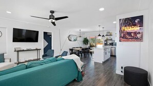 A modern living room with a sofa, a dining area, and a kitchen.