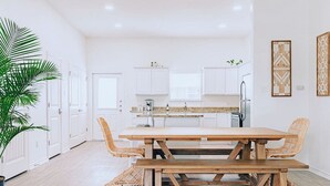 Una cocina moderna con armarios blancos, una mesa de comedor de madera y sillas de mimbre.