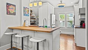 A modern kitchen with a central island, bar stools, and pendant lighting.
