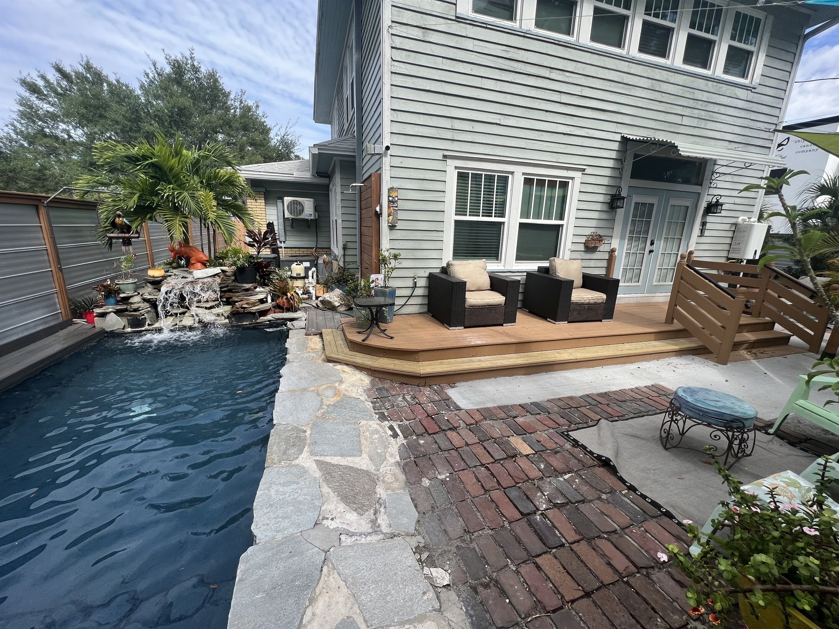 A backyard with a swimming pool, a wooden deck, and outdoor furniture.
