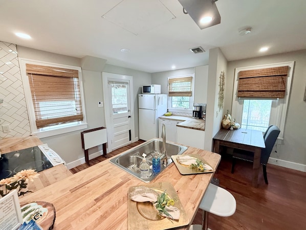 A modern kitchen with a wooden countertop, a sink, and a dining area with a table and chairs.