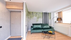 Una sala de estar moderna con un sofá verde, una mesita redonda con fruta y una lámpara.