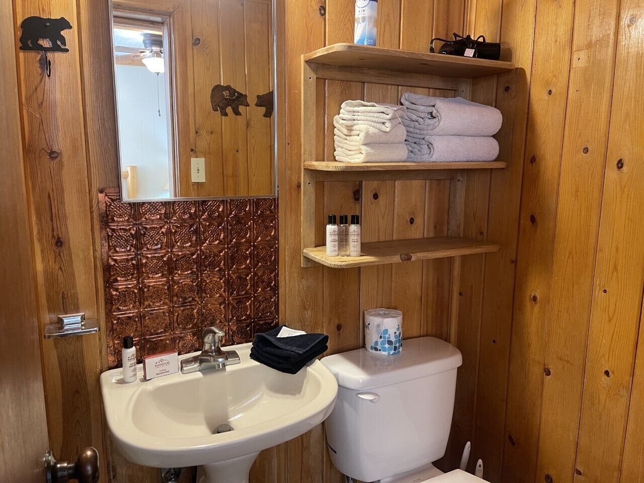 Un bagno in legno con lavabo, servizi igienici e mensole.