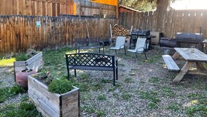 A backyard with a wooden fence, a barbecue grill, a picnic table, and outdoor seating. - Red River Condo #4 near Main Street (Red River)