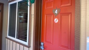 A red door with a number 4 sign, a window with blinds, and a green light fixture. - Red River Condo #4 near Main Street (Red River)